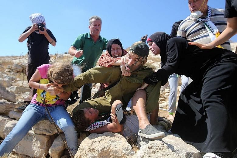 Pictures of Palestinians fighting to free a boy (above) held by an Israeli soldier during clashes between Israeli security forces and Palestinian protesters last Friday in the West Bank village of Nabi Saleh, near Ramallah, have gone viral, with peop