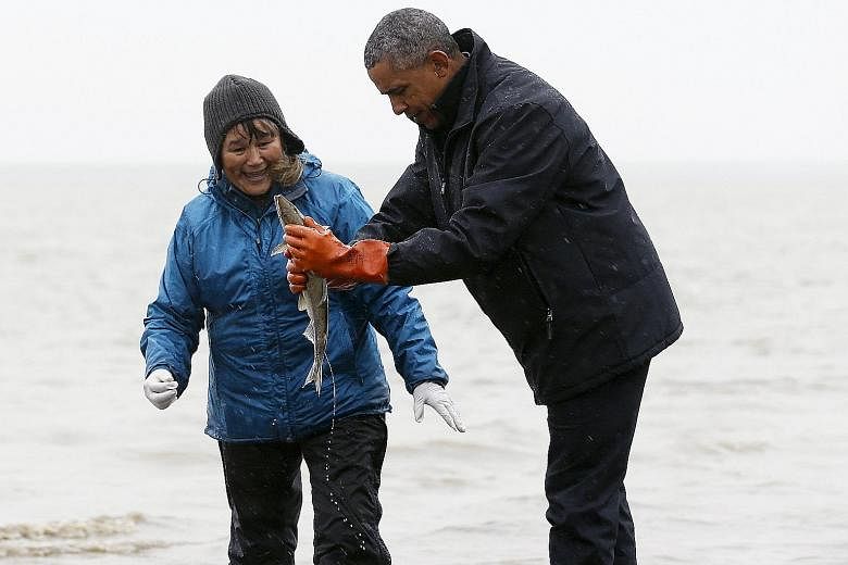US President Barack Obama holding the fish which excreted on his shoes at Bristol Bay in Alaska on Wednesday, which was the final day of his trip to the 49th US state.