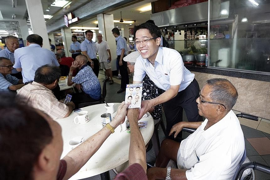 WP's candidate for East Coast GRC, Mr Gerald Giam, distributing fliers at the New Upper Changi Road Market and Food Centre yesterday while on a walkabout with his team.
