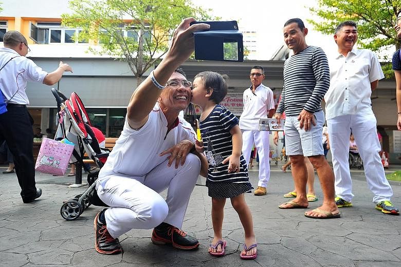 PAP's Dr Mohamad Maliki Osman getting a kiss on the cheek from two-year-old Ng Kai Xuan during the PAP East Coast GRC team's walkabout in New Upper Changi Road yesterday.