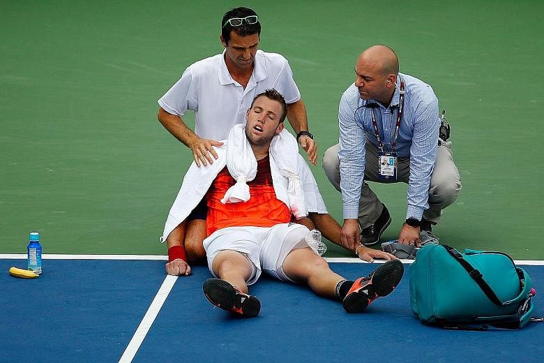 Jack Sock (centre), being treated by trainer Hugo Gravil (left) and a tournament official for heat exhaustion, was leading Ruben Bemelmans when he started cramping.