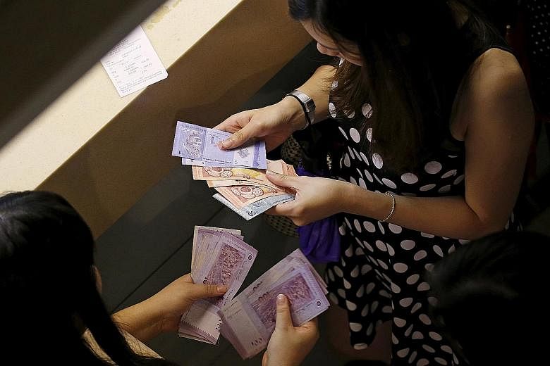 Customers counting their ringgit notes. The ringgit has seen losses of around 18 per cent this year, making it emerging Asia's worst performing currency.