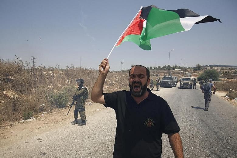 A protester brandishing a Palestinian flag during a demonstration against Jewish settlements in the West Bank village of Nabi Saleh, near Ramallah. Palestine's hopes of having its flag raised at the United Nations is an event that highlights its peop