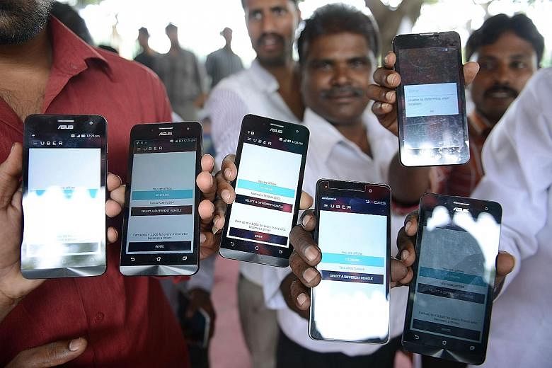 Indian drivers working for Uber, a US-based transport service, with company-issued mobile phones. The drivers alleged they were not making as much money as promised by Uber. Dropped calls could also affect their daily takings.