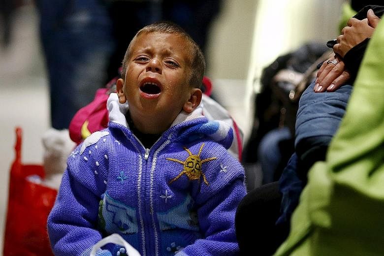 An exhausted Syrian boy crying after he arrived with his family on a train from Budapest's Keleti station at the railway station of the airport in Frankfurt, Germany, early yesterday. The refugee crisis is a responsibility for the rest of the world, 