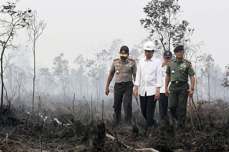 Mr Joko Widodo (second from left) is accompanied by police chief Badrodin Haiti (left) and military chief Gatot Nurmantyo (right) on a visit to an area in the South Sumatra district of Ogan Komering Ilir yesterday where there has been land burning.