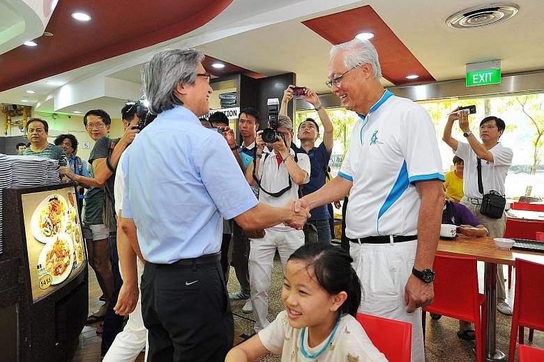 The Workers' Party's Mr Chen Show Mao (left) shaking hands with ESM Goh Chok Tong at a food court in Hougang Central when they met in the opposition-held ward yesterday. GE2015 REPORTS A4-12
