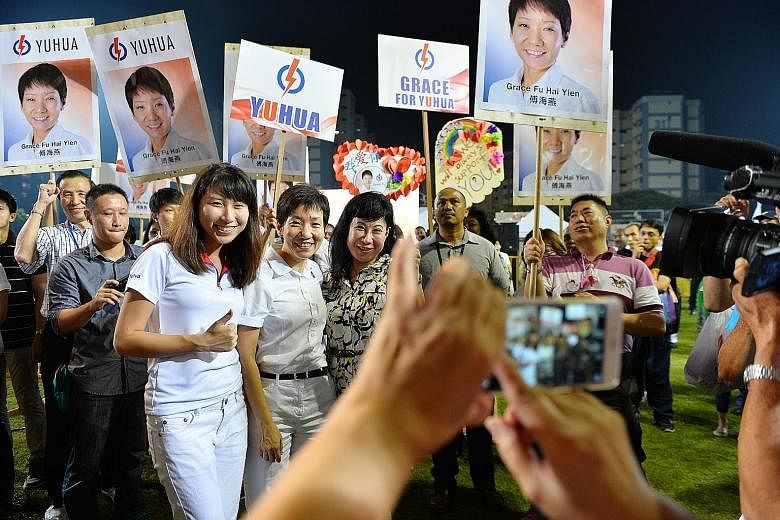 (Above) The PAP candidate for Yuhua SMC, Ms Grace Fu (front row, centre), taking a picture with her supporters at the party's rally in Jurong East Stadium last night.