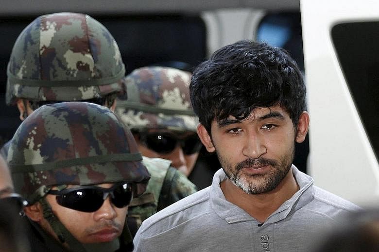 Bombing suspect Yusufu Mieraili, who the police say was arrested near the Cambodian border, being taken to a police station in Bangkok yesterday. He said he and four others reported to a man known as "Izaan".