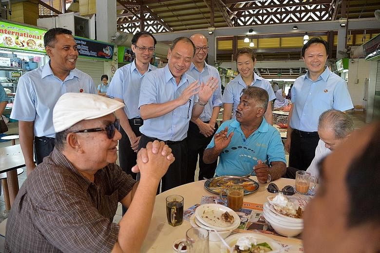 Mr Low Thia Khiang (clapping), secretary-general of the Workers' Party, with Marine Parade GRC candidates (from left) Firuz Khan, Yee Jenn Jong, Terrence Tan, He Ting Ru and Dylan Ng chatting with some diners at the Geylang Serai market yesterday. Th