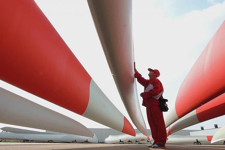 A worker checking wind-turbine blades in a Jiangsu factory. Many Asian markets fell after China cut its 2014 growth figure to 7.3 per cent.