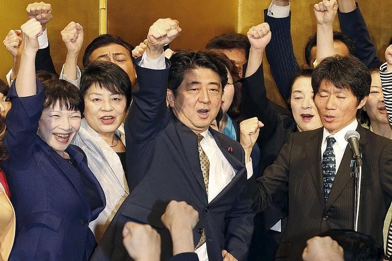 Japanese Prime Minister Shinzo Abe (centre) shouting slogans with fellow lawmakers during a kick-off ceremony in Tokyo yesterday for the party leadership polls, in which he was unopposed and won a rare second term.