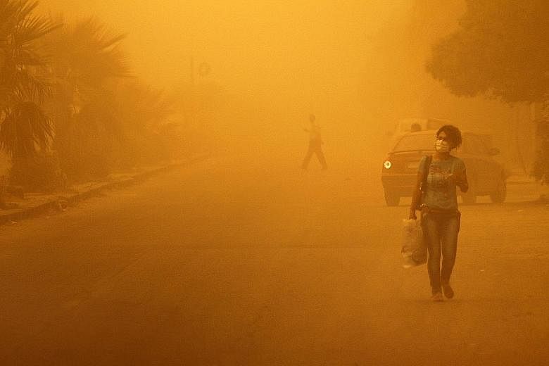A woman wears a face mask as she walks through a sandstorm in Homs, Syria. A massive sandstorm swept across parts of the Middle East yesterday, killing two people and causing hundreds to be hospitalised. The clouds of dust engulfed Lebanon, Israel, J