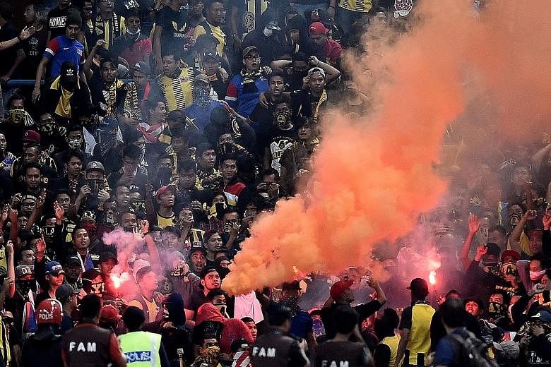 Malaysian football fans burning flares in the stands during Tuesday's World Cup qualifier against Saudi Arabia. Flares thrown onto the pitch caused the game to be abandoned, with the Asian Football Confederation saying it is "extremely disappointed".