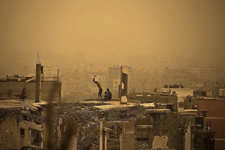 Palestinian workers in Gaza City removing debris from a building, one of many which were destroyed during the 50-day war between Israel and Hamas militants last year, amid a sandstorm on Tuesday.