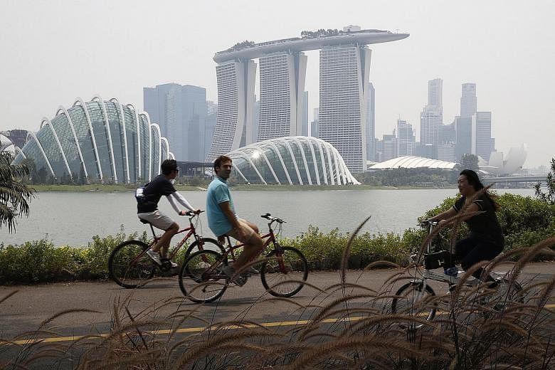 Cyclists at Bay East, Gardens by the Bay, at 1.15pm yesterday. The National Environment Agency has forecast the 24-hour PSI to be in the mid to low end of the unhealthy range. This may even move into the high end of the moderate range if winds stay f