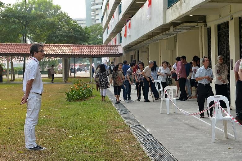 Mr Lim Swee Say looking at the voters at the New Upper Changi Road polling station yesterday.