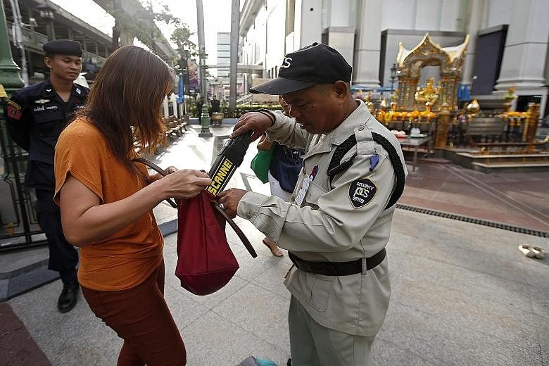 A security guard conducting checks at the Erawan Shrine this week. The investigation into the bomb attack has gained momentum with information given by one of two detained suspects.