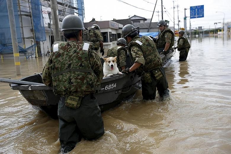 A pet dog being ferried to safety in Joso yesterday. Some 4,500 people were forced to stay in more than 20 facilities, such as schools, public halls and gymnasiums, as the region suffered a halt to water and power supply for the third night.