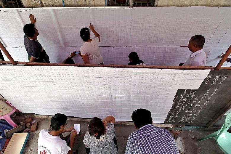 People checking their names on a voters' list in Kamayut town in Yangon, Myanmar, yesterday. The three main power blocs - the ruling military-backed Union Solidarity and Development Party, the opposition National League for Democracy (NLD) and ethnic