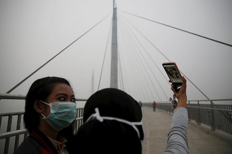Girls posing for a photograph on the haze-shrouded Batanghari River bridge in Jambi, Sumatra, yesterday.