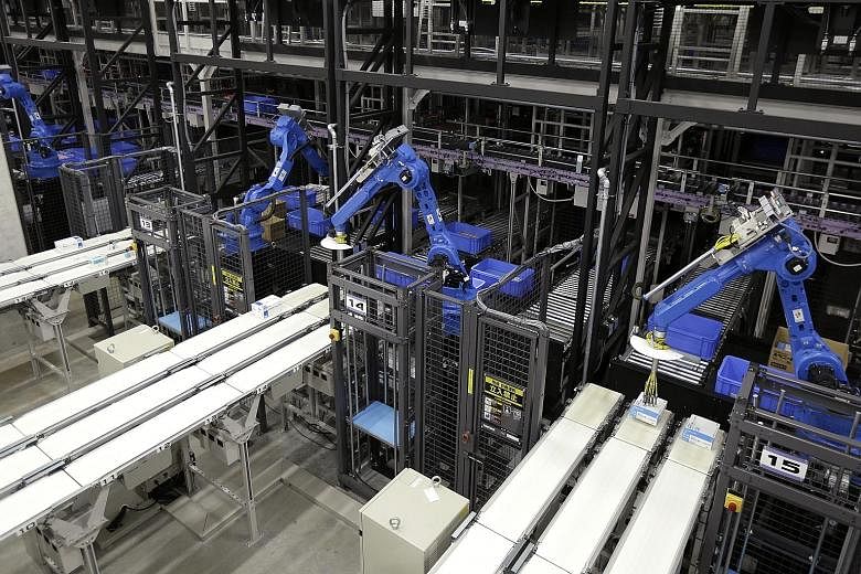 Robots pick items to place on conveyors for sorting at a centre operated by Toho. By 2025, robots could shave off 25 per cent of factory labour costs in Japan, according to Boston Consulting Group.