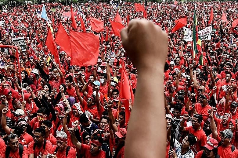 Demonstrators (left) waving flags and chanting slogans at the rally in Kuala Lumpur yesterday. Although riot police were present to ensure the situation did not get out of hand, some clashes broke out (below).