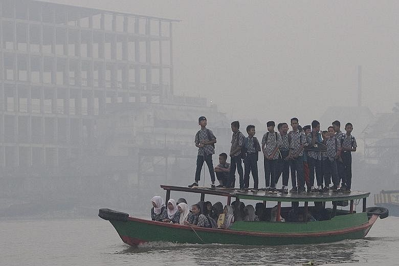 Indonesian students crossing the Ogan River on a wooden boat in the haze as they head to their school in Palembang, South Sumatra, yesterday.