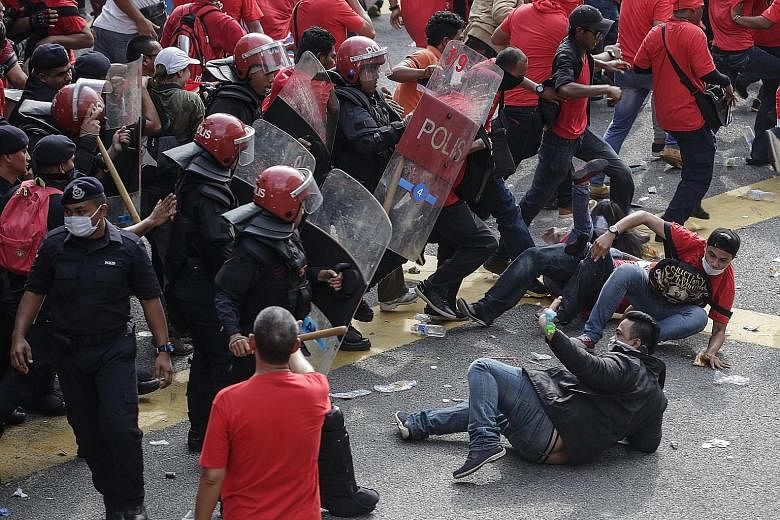 Demonstrators (left) waving flags and chanting slogans at the rally in Kuala Lumpur yesterday. Although riot police were present to ensure the situation did not get out of hand, some clashes broke out (below).