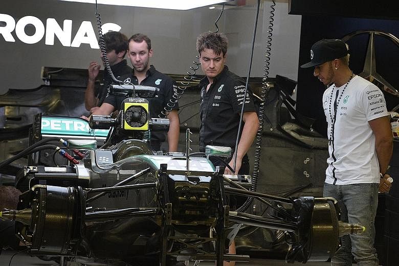 Lewis Hamilton inspecting his Mercedes car in the garage at the F1 Pit Building. He will match Sebastian Vettel's three victories here with a win on Sunday, which will take him closer to retaining his world title.