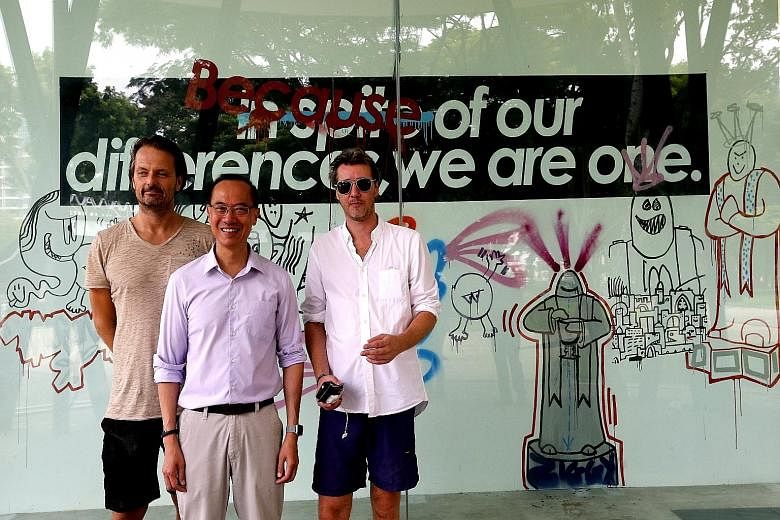 Mr George Yeo, flanked by German artists Niklas Bo Beckert (left) and Dennis Kaun, at the unveiling of a mural wall featuring graffiti art by the duo at Bedok Reservoir Park yesterday. They were also responsible for the artwork on four Berlin Wall pa