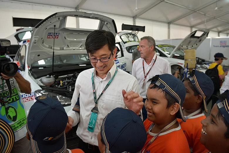 Minister of State for Trade and Industry, Mr Teo Ser Luck, with kids from five local voluntary welfare organisations at the Singapore Airlines Singapore Grand Prix yesterday. The 84 kids enjoyed a full F1 experience, enjoying the sights and sounds of