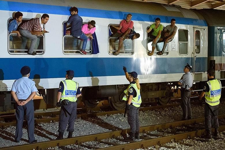 Migrants sitting on the windows of a train at the railway station near the border between Slovenia and Croatia on Thursday.