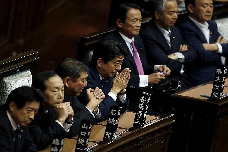 Mr Shinzo Abe (fourth from left), with his Cabinet members in the Lower House of Parliament in Tokyo last Friday. His government pushed through contentious legislation allowing troops to fight abroad for the first time since World War II despite publ