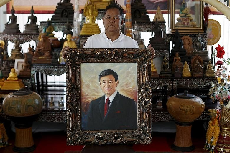Red-shirt leader Kwanchai Praipana posing with a painting of former PM Thaksin in his office in Udon Thani. Mr Kwanchai was shot in the arm in a drive-by shooting at his rural home when Bangkok was paralysed by protests preceding last year's coup.