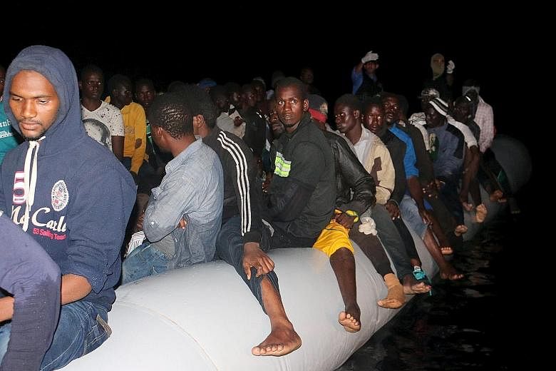 Migrants crowd onto a rubber dinghy in which they hope to reach Europe, after being detained at a Libyan navy base in the coastal city of Tripoli yesterday.