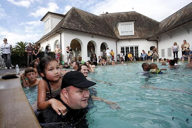 Kim Dotcom swimming with his daughter Kaylo at a pool party at his mansion in Auckland last year. The US says Dotcom and three co-accused Megaupload executives cost US film studios and record companies more than US$500 million by encouraging paying u