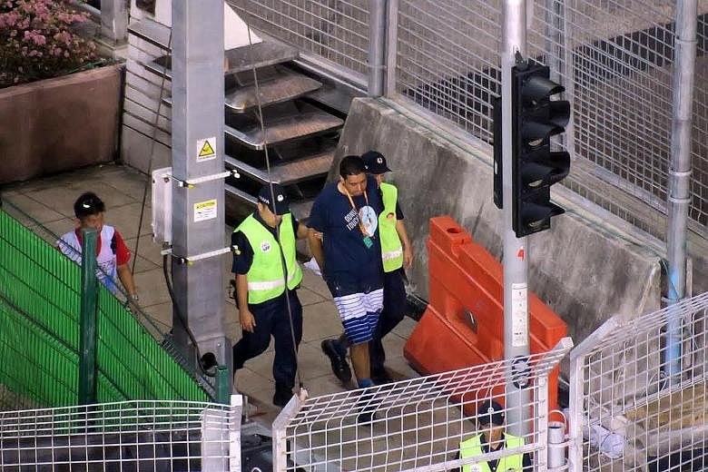 A man being led away after invading the track during the Singapore Grand Prix on Sunday. He has been arrested and is assisting police with investigations.
