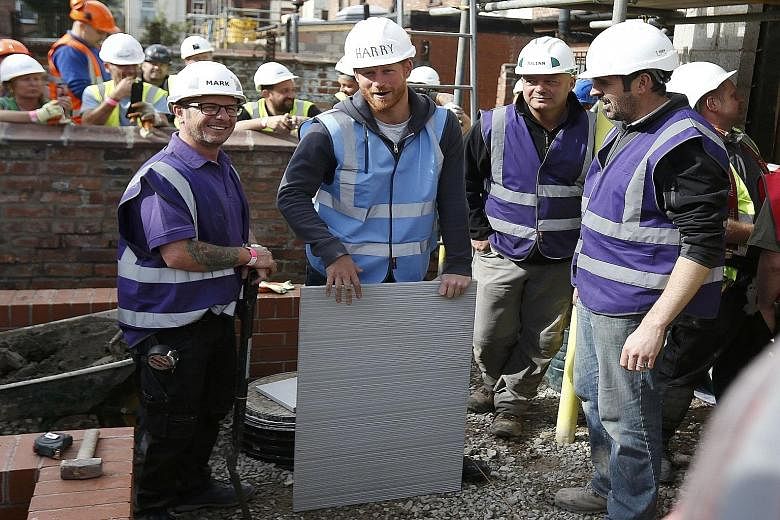 Britain's Prince Harry preparing to lay some paving slabs during a visit to Manchester yesterday. He and his brother, Prince William, have pitched in as part of the BBC television series DIY SOS, which turns several empty properties on a derelict str