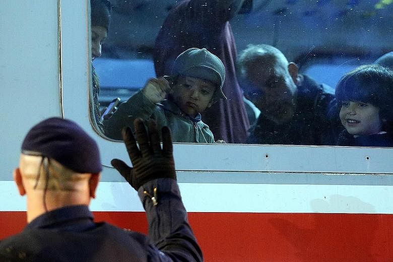A police officer waving to migrant children on a train heading to the Croatian- Hungarian border at a station in Croatia's east.
