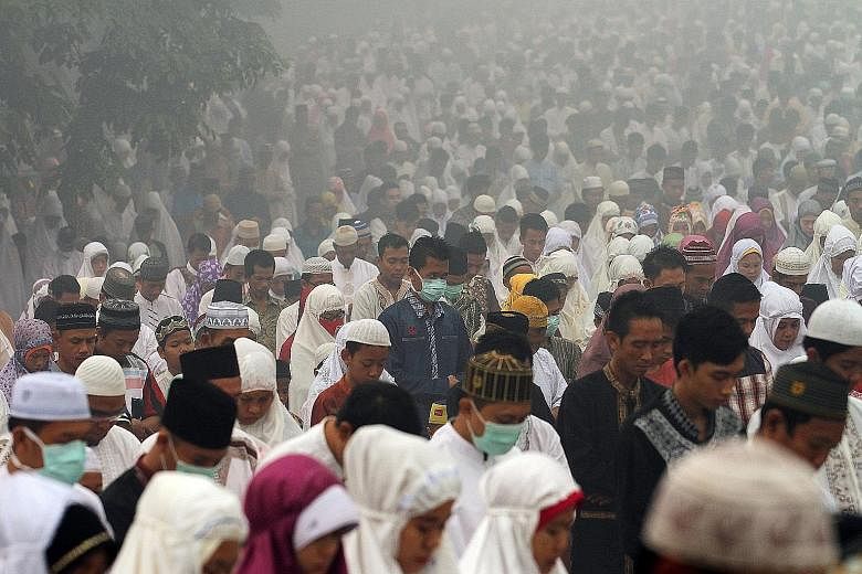 Indonesian Muslims performing prayers marking Hari Raya Haji yesterday amid the worsening haze from forest fires, in Palembang, South Sumatra province, yesterday. BNPB spokesman Sutopo Purwo Nugroho said yesterday that 2,081 hot spots were recorded i