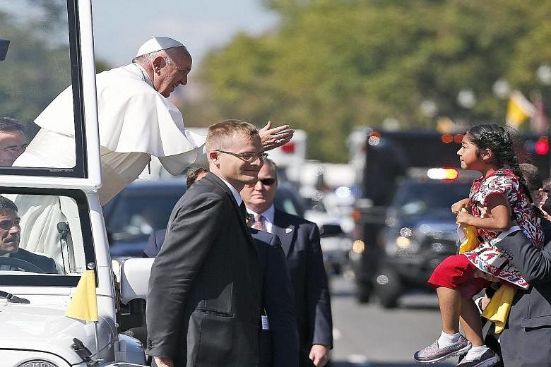 Pope Francis waving five-year-old Sofia Cruz through security after she had climbed over a barrier and darted out to hand him a letter. Tens of thousands had flocked to Washington, DC to catch a glimpse of the Pope, who is making his inaugural visit 
