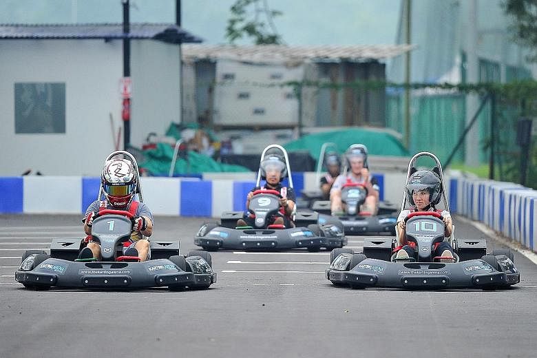 Reporter Melissa Heng (left) tries an electric go-kart. Eleven-year-olds Ollie Blakey (sitting from left) and Sam Stewart trying out the simulators. The $1.4-million electric karting circuit (above) in Turf City, Bukit Timah, has a 500m-long track wi