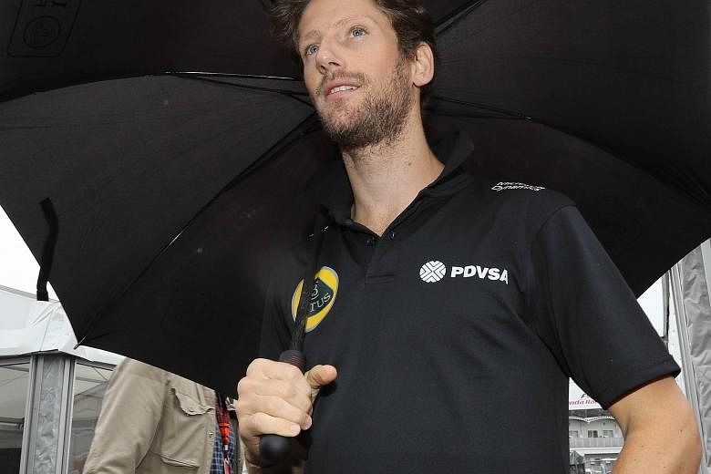 Lotus driver Romain Grosjean finding shelter under an umbrella at Suzuka. He had to conduct his press briefing out in the paddock area.