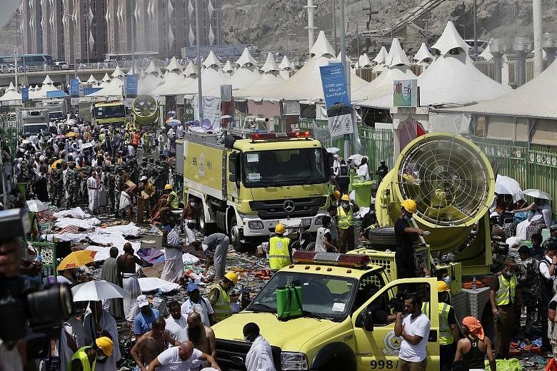 Members of the Saudi emergency services moving among the bodies of those killed in the stampede as pilgrims looked on yesterday in Mina, about 5km from Mecca. The Saudi civil defence service said more than 220 ambulances and 4,000 rescue workers had 
