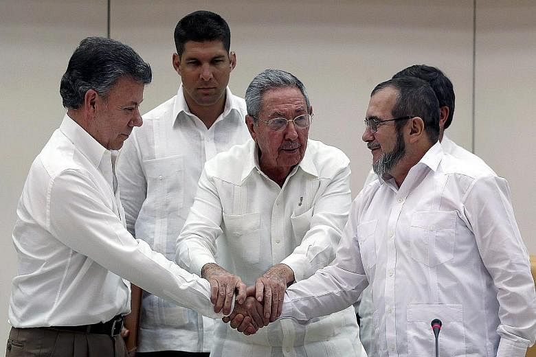 Cuban President Raul Castro (centre) holding the hands of Colombian President Juan Manuel Santos (far left) and Farc leader Timoleon "Timochenko" Jimenez during a press conference on Wednesday. The Colombian government and the rebel group reached a p