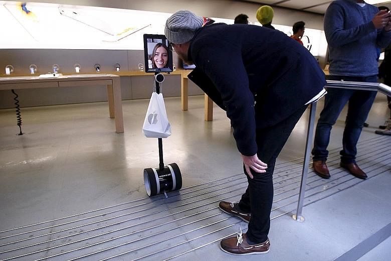 A man talking to Ms Lucy Kelly yesterday on an iPad attached to a remote-controlled scooter. Since she was at work, she sent her "robot" to queue and buy the new iPhone 6s models at the Apple store in Sydney.