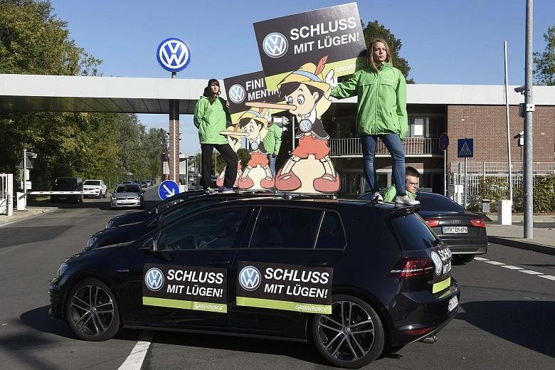 Greenpeace activists standing on the roof of a Volkswagen car holding banners that say "No more lies", outside the company's headquarters in Wolfsburg, Germany. The carmaker used a "defeat device" that put a lid on vehicle emissions but only during t