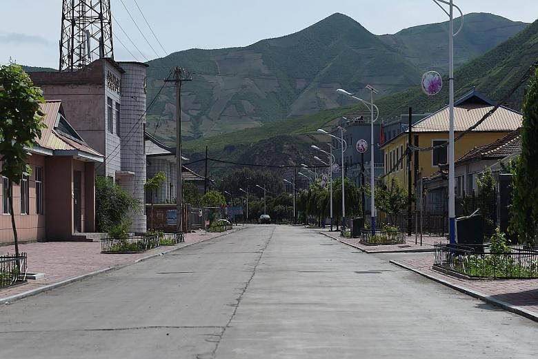 A deserted street in the Chinese border village of Nanping, with the hills of North Korea behind. After a spate of murders - allegedly by frontier-crossing intruders - frightened villagers are keen to leave.