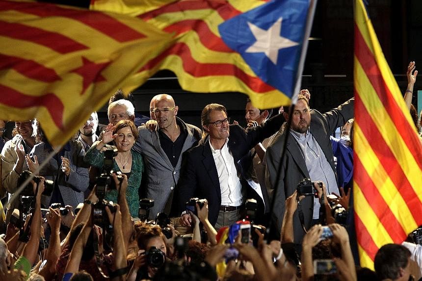 Pro-sovereignty party Junts pel Si (Together For Yes) leaders Raul Romeva (centre), Artur Mas (second from right) and Oriol Junqueras (right) celebrating in Barcelona, Catalonia's capital, after separatist groups won the majority of seats in the regi